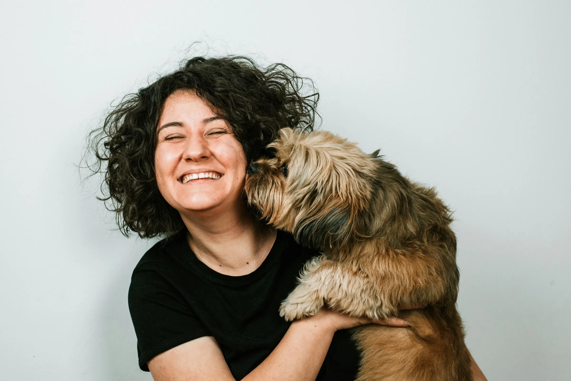 A dog giving its laughing owner a kiss